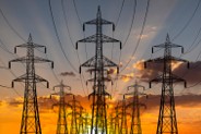 Electricity pylons next to each other with a sunset in the background